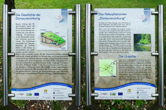 Blick auf zwei nebeneinander angebrachte farbige Hinweisschilder zum Thema Donauversinkung.