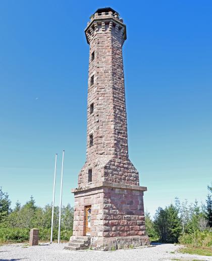 Blick auf einen gemauerten Aussichtsturm mit viereckigem Sockel und sechseckigem Turm. Der Turm steht frei auf einer Anhöhe. Die Aussichtsplattform ist überdacht.
