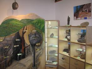 Blick in einen Museumsraum. Rechts sind Regale und ein Schaukasten mit Gesteinsstücken aufgebaut. Links ist eine Schnittzeichnung vom geologischen Aufbau des Kaiserstuhls zu sehen.