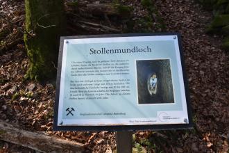 Blick auf eine farbige Schautafel, aufgestellt am bergbauhistorischen Lehrpfad Birkenberg bei Bollscheil-St. Ulrich. Die Tafel gibt Auskunft zum Thema Stollenmundloch, ergänzt durch ein Foto.