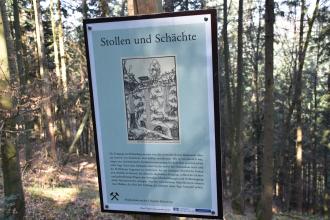Blick auf eine kleine Schautafel, aufgestellt am bergbauhistorischen Lehrpfad Birkenberg bei Bollschweil-St. Ulrich. Die Tafel gibt Auskunft über Stollen und Schächte, ergänzt durch eine alte Illustration in Schwarzweiß.