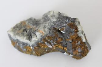 Großaufnahme eines kleinen Gesteinsstückes. Die Bruchseite im Vordergrund zeigt gelbliche bis rötliche sowie dunkelgraue Stellen. Die Oberseite des Gesteins ist weißlich bis grau und kristallin.