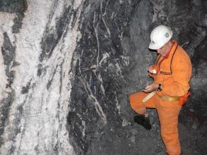 Blick auf einen Schwerspatgang in der Grube Clara. Rechts ein Bergbaumitarbeiter in oranger Schutzkleidung.