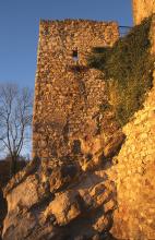 Blick auf den Mauerturm einer Burgruine, rötlich verfärbt von der Abendsonne. Der Turm steht auf einem ebenfalls rötlichen Felsen.