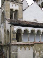 Ansicht eines Kirchturmes und einer davor verlaufenden Galerie in romanischem Baustil. Mauerwerk und Säulen haben eine grünliche Farbe, der dazwischen liegende Verputz ist weiß.
