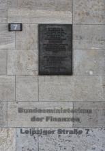 Hausfassade aus grauen Gesteinsplatten mit bräunlichen Flecken und Schlieren. Angebracht ist auch eine Tafel, eine Hausnummer und die Anschrift „Bundesministerium der Finanzen“.