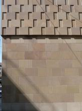 Teilansicht einer Hausfassade; verwendet wurden hier hellbraune bis rötlich braune glatte Mauersteine, die im unteren Bildteil flächig, im oberen Bildteil versetzt zueinander angeordnet wurden.