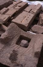 Auf Paletten ausgelegte Gebäudeteile aus römischer Zeit, gefertigt aus rötlich grauem Gestein.
