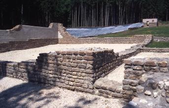 Blick auf die Überreste eines Gebäudes aus der Römerzeit; zu sehen sind die niedrigen Mauern ehemaliger Wohnräume. Im Hintergrund links wurde eine Mauer mit neuem Material aufgefüllt.                   