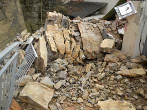 Das Bild zeigt nach einem Felssturz angehäufte Gesteinsmassen auf dem Terrassendach eines Wohnhauses.