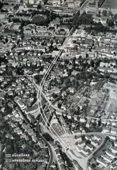 Schwarzweiße Teilansicht von Stuttgart, als Luftbild gemacht, mit dem eingezeichneten Verlauf des geplanten beziehungsweise gebauten Wagenburgtunnels. Oben rechts ist der Bahnhof zu erkennen, unten rechts die Öffnung der Südröhre.