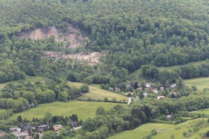 Luftbild der Hangrutschung bei Mössingen-Öschingen (Foto: Polizeihubschrauberstaffel Baden-Württemberg) Luftbild eines bewaldeten Hanges, an dessen linker Seite ein großes Stück abgebrochen und zu Tal gerutscht ist, bis nahe einer kleinen Siedlung rechts unten.