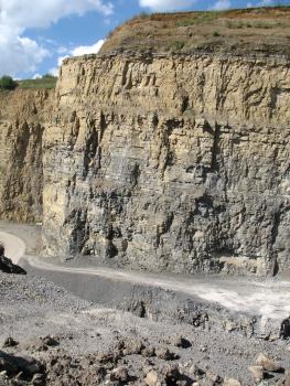 Oberer Muschelkalk bei Herrenberg-Haslach Blick auf eine stufenförmig von links nach rechts aufsteigende Steinbruchwand mit oben gelbbraunem und unten grauem Gestein.