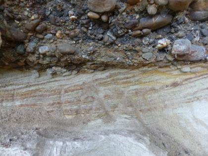 Böschungsaufschluss östlich vom Haldenhof Nahaufnahme zweier unterschiedlicher, aufeinanderliegender Gesteinsschichten. Oben liegt unregelmäßiges, mit kleinen und größeren Steinen verbackenes, bläulich braunes Gestein. Unten zeigt sich helles, streifiges und eher glattes Gestein.