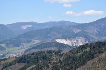 Blick vom Rappenschrofen nach Nordosten zur Hornisgrinde Blick aus großer Höhe auf Reihen bewaldeter Berge. Im Mittelgrund rechts sowie links im Hintergrund sind Steinbrüche erkennbar. Links unten liegt eine Siedlung.