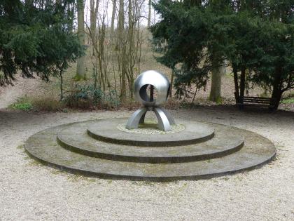 Schwefelquelle nördlich von Östringen Das Foto zeigt eine Schwefelquelle, eingefasst in eine moderne Kugelform mit Metallbögen als Füße. Die Konstruktion steht auf drei runden flachen Treppen am Rand einer Lichtung.