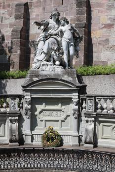Die Skulpturen an der Fassung der Donauquelle in Donaueschingen Teilansicht der steinernen Einfassung der Donauquelle mit Brüstung und Reliefsockel. Auf dem Sockel steht eine aus hellem Stein gemeißelte Figurengruppe. Sie stellt Mutter Baar und deren Tochter Donau dar.