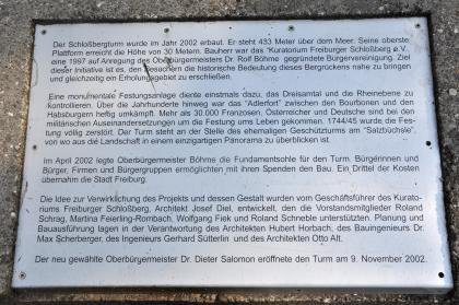 Informationstafel am Freiburger Schlossbergturm Blick auf eine rechteckige Informationstafel mit viel Text zur Entstehung des Freiburger Schlossbergturmes.