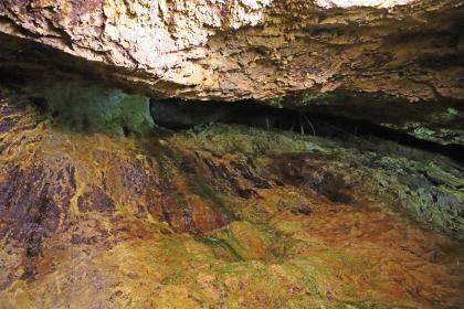 Blick nach oben in den Abbau auf dem Schindlergang des Silberbergwerks Teufelsgrund bei Münstertal Aufwärts gerichteter Blick auf eine quer durchs Bild verlaufende Spalte zwischen Gesteinswänden. Der Bereich um die Spalte ist grünlich verfärbt, zum Vordergrund hin folgen rostbraune Farben.
