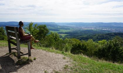 Aussichtspunkt auf dem Hohenstaufen Das Bild zeigt einen Aussichtspunkt mit weitem Blick auf das östliche Albvorland um den Hohenstaufen. Links ist eine von einem Künstler gefertigte Sitzbank mit Figur aufgestellt.