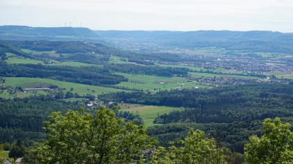 Albvorland bei Salach und Süßen, Blick in das Filstal – Links die ehem. Burg Staufeneck am Südrand des Rehgebirges – Hinten Talausgang der Fils bei Gingen a. d. F. Blick von erhöhtem Standort auf ein stark besiedeltes Tal mit bewaldeten Höhenzügen im Hintergrund. Von den Höhen links und rechts des Tales schieben sich Waldzungen in die Ebene.