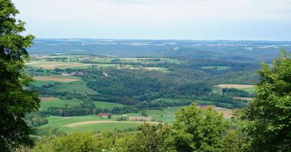 Blick vom Hohenstaufen über das Remstal bei Lorch hinweg nach Norden – Im Vordergrund sieht man die durch die bewaldeten Keuperhänge des Beutentals zerschnittenen Unterjuraplatten östlich von Wäschenbeuren Über Baumkronen hinweg blickt man auf eine hügelige, stark bewaldete Landschaft. Zwischen den Waldflächen liegen Wiesen und Äcker.