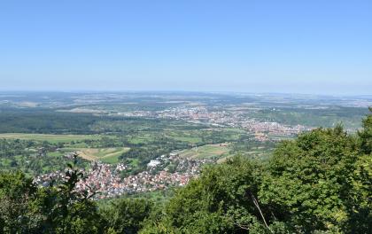 Blick von erhöhtem Standort auf eine weite, flachwellige Landschaft mit Feldern, Waldstücken und zahlreichen Ortschaften.