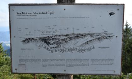 Informationstafel zu Geologie und Landschaft – Blick vom Schauinslandgipfel nach Norden Das Bild zeigt eine Schautafel vom Schauinsland-Gipfel. Auf der Tafel ist eine mit Namen versehene Zeichnung der zahlreichen Berge, die man von diesem Standort aus sehen kann. Dazu wird der Abschnitt Kaiserstuhl – Hinterwaldkopf näher erläutert.