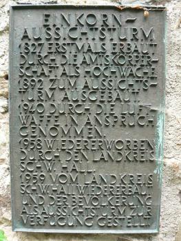 Informationstafel zur Geschichte des Aussichtsturms auf dem Einkorn Das Foto zeigt eine graugrüne Texttafel mit erhabenen Buchstaben. Die Tafel erzählt von der Geschichte des Aussichtsturmes auf dem Einkorn.