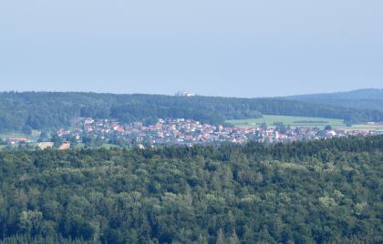 In Richtung Nordnordosten kann man vom Sternbergturm aus in der Ferne die Ruine Hohenneuffen erkennen. Blick von erhöhtem Standpunkt auf langgestreckte bewaldete Bergrücken, die bis zum Hintergrund reichen. Dazwischen, in einer Senke, hat sich eine Stadt ausgebreitet. Auf dem hinteren Berg ist eine größere Burgruine erkennbar.