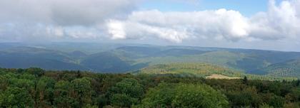 Blick vom Katzenbuckel über den Zentralen Sandstein-Odenwald nach Norden und Nordosten Vom Aussichtsturm auf dem Katzenbuckel geht der Blick über ausgedehnte Waldflächen und bewaldete Berge. Im dunstigen und wolkigen Hintergrund ist rechts der Bildmitte ein Sendeturm zu erkennen.