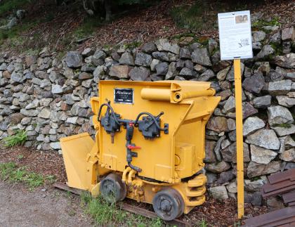 Wurfschaufellader beim Museumsbergwerk Schauinsland Das Foto zeigt einen alten gelben Wurfschaufellader. Das Arbeitsgerät im Bergbau steht vor einer mit Mauersteinen gesicherten Böschung.