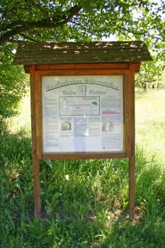 Infotafel zum Silberstollen Gabe Gottes Großerlach Blick auf eine überdachte Informationstafel zum Großerlacher Silberstollen "Gabe Gottes". Die darauf befindlichen Texte und Zeichnungen sind verglast und mit Holz eingerahmt. Man sieht unter anderem Lage und Form des Stollens sowie die Geologie.