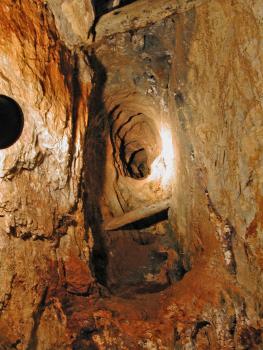 Schacht in der Grube Segen Gottes bei Haslach im Kinzigtal Blick in einen alten Bergwerksschacht mit Holzstützen und einer trichterförmigen Vertiefung an der hinteren Wand. Die Wände haben eine rötlich braune Färbung.