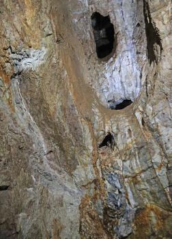 Blick nach oben in einen der hohen Abbaue im Besucherbergwerk Finstergrund bei Wieden Aufwärts gerichteter Blick auf Wände und Decke in einem Besucherbergwerk. Im violettgrauen, ovalen Deckenbereich sind mehrere Löcher erkennbar. Die Wände sind bräunlich grau mit rötlichen Schlieren.