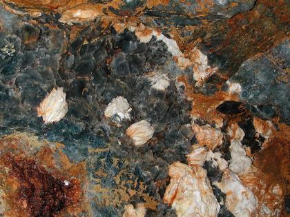 Nahaufnahme des Fluss- und Schwerspatgangs in der Grube „Segen Gottes“ bei Haslach im Kinzigtal Nahaufnahme von dunkelgrauen Gesteinskristallen, die von weißen und rötlich braunen Gesteinsbildungen durchzogen sind.