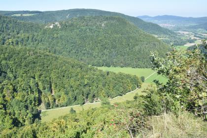 Blick vom Eppenzillfelsen nach Nordwesten zum Runden Berg Blick von erhöhtem Standort auf drei bewaldete, nach links hin aufsteigende Berge. Auf dem mittleren Berg sind freistehende Felsen zu erkennen. Nach rechts zum Bildrand hin verläuft ein teils besiedeltes Tal.