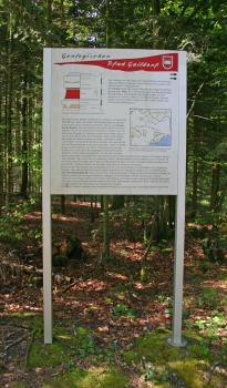 Gezeigt wird hier eine größere Informationstafel des Geologischen Pfades in Gaildorf. Die Tafel erzählt mit Texten und farbigen Grafiken vom Keuper. Die Tafel ist vor einem dichten, schattigen Wald aufgestellt.