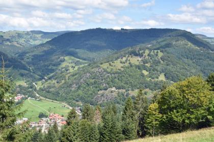 Blick vom Haldenfels nördlich von Tunau über Utzenfeld zum Knöpflesbrunnen Blick von erhöhtem Standort auf einen nach rechts aufsteigenden bewaldeten Berg. Die teils bewaldete, teils baumfreie Kuppe des Berges knickt nach links hin ab und verläuft dort fast eben. Links unten, am Fuß des Berges, liegt eine Ortschaft.