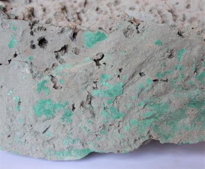 Malachit auf Rotliegend-Sediment aus dem Stollen bei Herten (Rote Höhle) Teilansicht der Bruchseite eines Malachitstückes. Das Gestein ist hellgrau gefärbt und durchsetzt mit grünlichen Einlagerungen.