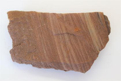 Eisenoolith, Murchisonae-Schichten (jmES) In Großaufnahme fotografiertes Bruchstück von Eisenoolith, mit rötlich brauner Oberfläche und helleren, schräg nach unten verlaufenden Bändern.