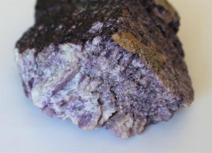 Quarz (weiß-lila) aus dem Steinbruch bei Aubach Nahaufnahme von der Bruchkante eines Quarzstückes. Die Bruchfläche besteht aus weißen bis lilafarbenen Kristallen, die oben sichtbare Außenhülle ist schwarz bis grünlich.