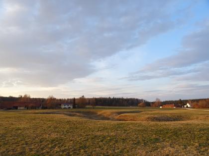 Uvala (Dolinenkette) auf einer Wiese bei Zang, Lkr. Heidenheim, Östliche Schwäbische Alb Zu sehen sind mehrere grabenartige Vertiefungen und Ausbuchtungen auf einer Wiese. Den Hintergrund begrenzen einzelne Häuser sowie ein Waldstreifen.