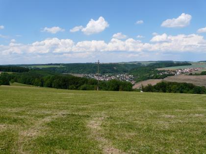 An der Mündung des Langenbachs in den Kocher liegt Weißbach. Das Kochertal ist bis in den Mittleren Muschelkalk eingetieft und deshalb entsprechend breit ausgeräumt. Das Bild zeigt eine zur Mitte hin abfallende große Grünlandfläche. Dahinter schließen sich Wälder sowie links ansteigende Rebhänge an. In einer Senke liegt eine größere Siedlung. Im Hintergrund sind bewaldete Hänge zu erkennen.