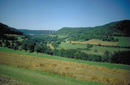 Blick ins untere Bühlertal bei Braunsbach-Geislingen Das Bild zeigt ein weites, teilweise bewaldetes Tal mit Grün- und Ackerflächen. Von links nach rechts ziehen sich Höhenzüge entlang; auch sie bewaldet. Im Hintergrund verbindet eine Autobahnbrücke zwei der Höhen.
