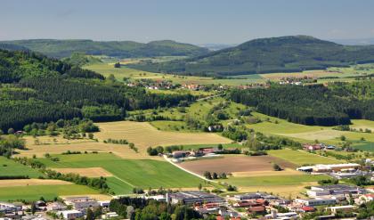 Die Baaralb-Berge südwestlich von Spaichingen Das Bild zeigt eine aus großer Höhe aufgenommene wellige Ackerlandschaft mit Besiedlung im Vordergrund sowie Waldflächen rechts und einer bewaldeten Höhe links. Im Hintergrund sind weitere bewaldete Anhöhen gut erkennbar.