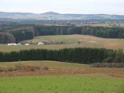Hegaualb bei Emmingen-Liptingen – Blick nach Südwesten über den Lehenholzer Hof und Bisendorf zum Neuhewen Der Blick geht über hochgelegene Ackerflächen und Waldstreifen im Mittel- und Hintergrund zu einer weiteren Hochfläche mit kegelförmiger Erhebung in der Bildmitte.