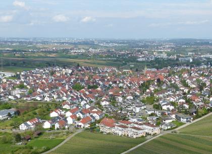 Der Südosten des Neckarbeckens und der Anstieg des Schurwalds bei Weinstadt-Beutelsbach Aus großer Höhe blickt man auf eine weite Ebene mit Siedlungen im Vorder- und Hintergrund. Dazwischen liegen Reb- und Ackerflächen.