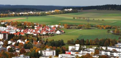 Übergang vom Buntsandsteinschwarzwald (Baar-Schwarzwald) zu den Baar-Gäuplatten bei Villingen Von bewaldeten Höhenzügen und Hügelkuppen im Hintergrund reicht der Blick nach vorn, wo eine wellige Acker- und Grünlandschaft rechts an eine größere Siedlung links und im Vordergrund grenzt.