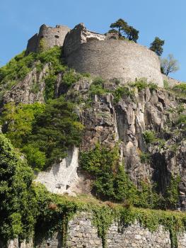 Festung Hohentwiel – Blick auf die Südwestecke der oberen Festung mit dem „Rondell Augusta“ Aufwärts gerichteter Blick auf einen Teil der Festung Hohentwiel. Zu sehen ist ein vorgelagerter, oben eingebrochener runder Turm, der auf grauem, teils stark bewachsenem Vulkangestein sitzt.